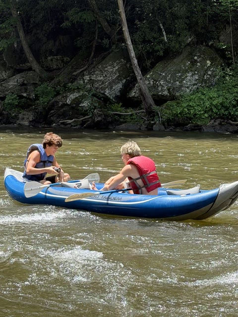 Two people paddling an inflatable kayak down a river