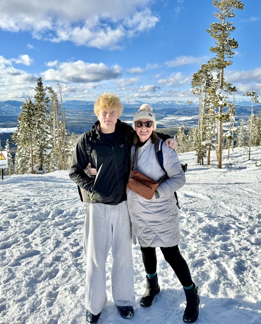 Two people at a snowy mountain summit on a clear day