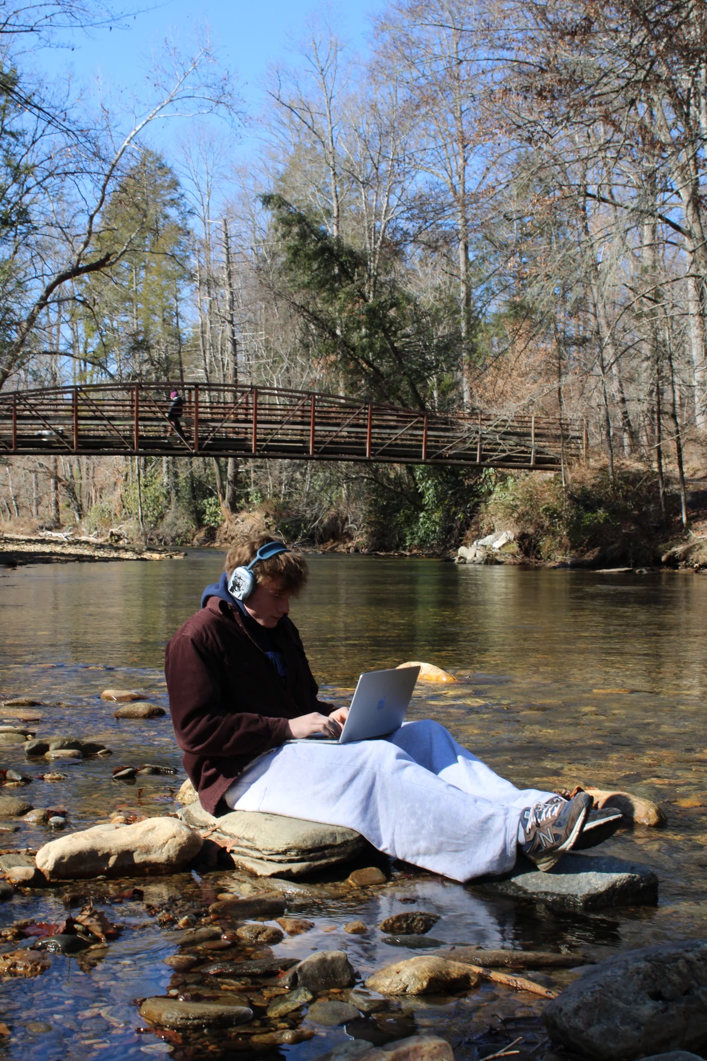 Ezra Jacobs, founder of Lazy Marketing, working on a laptop on the rocks in the middle of a river